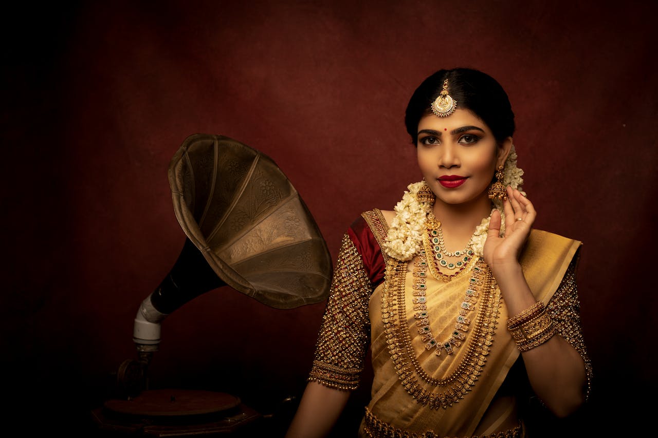 Mastering the First Impression: Your intriguing post title goes here Indian bride in traditional attire with gold jewelry, posing beside a vintage phonograph.